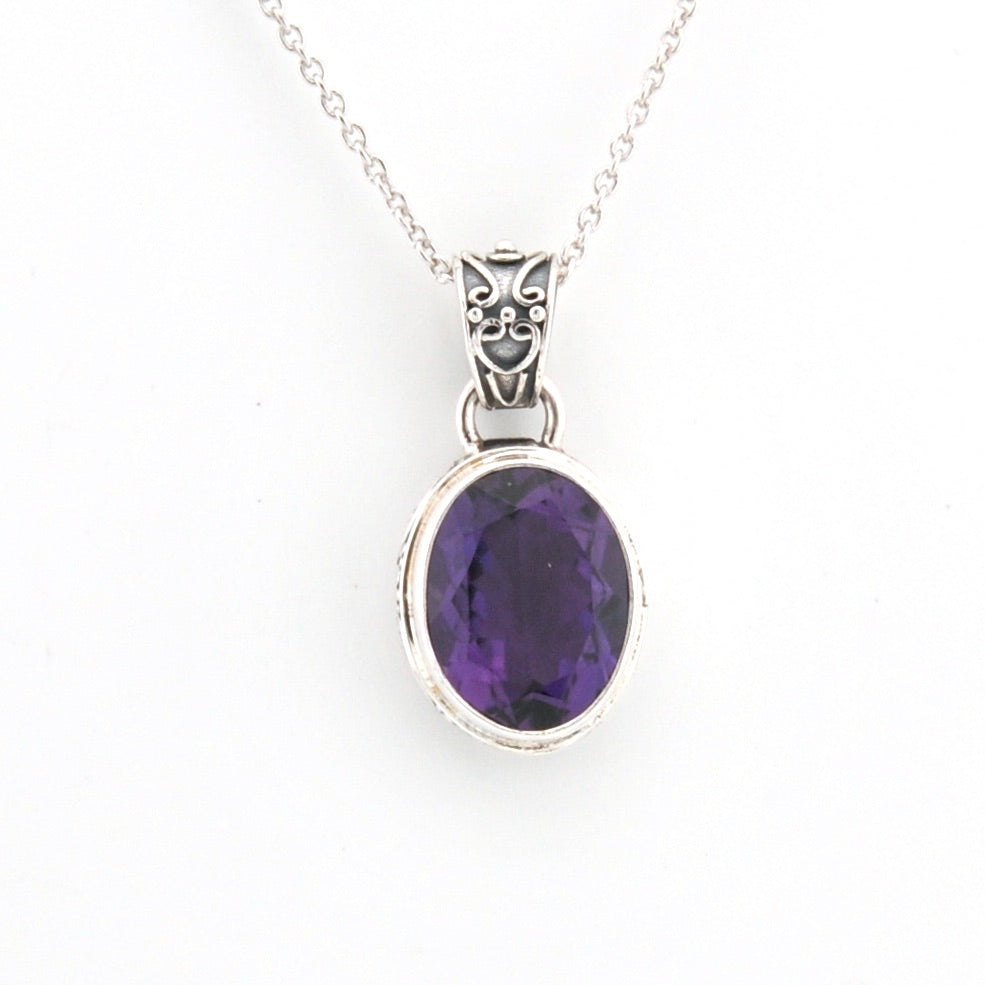 Silver pendant with a purple gemstone on a white background