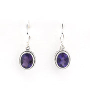 Pair of silver earrings with purple gemstones on a white background