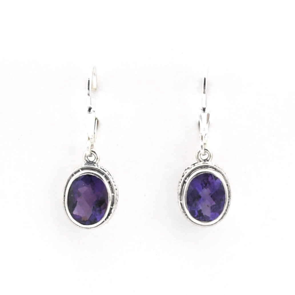 Pair of silver earrings with purple gemstones on a white background