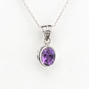 Silver pendant with a purple gemstone on a white background