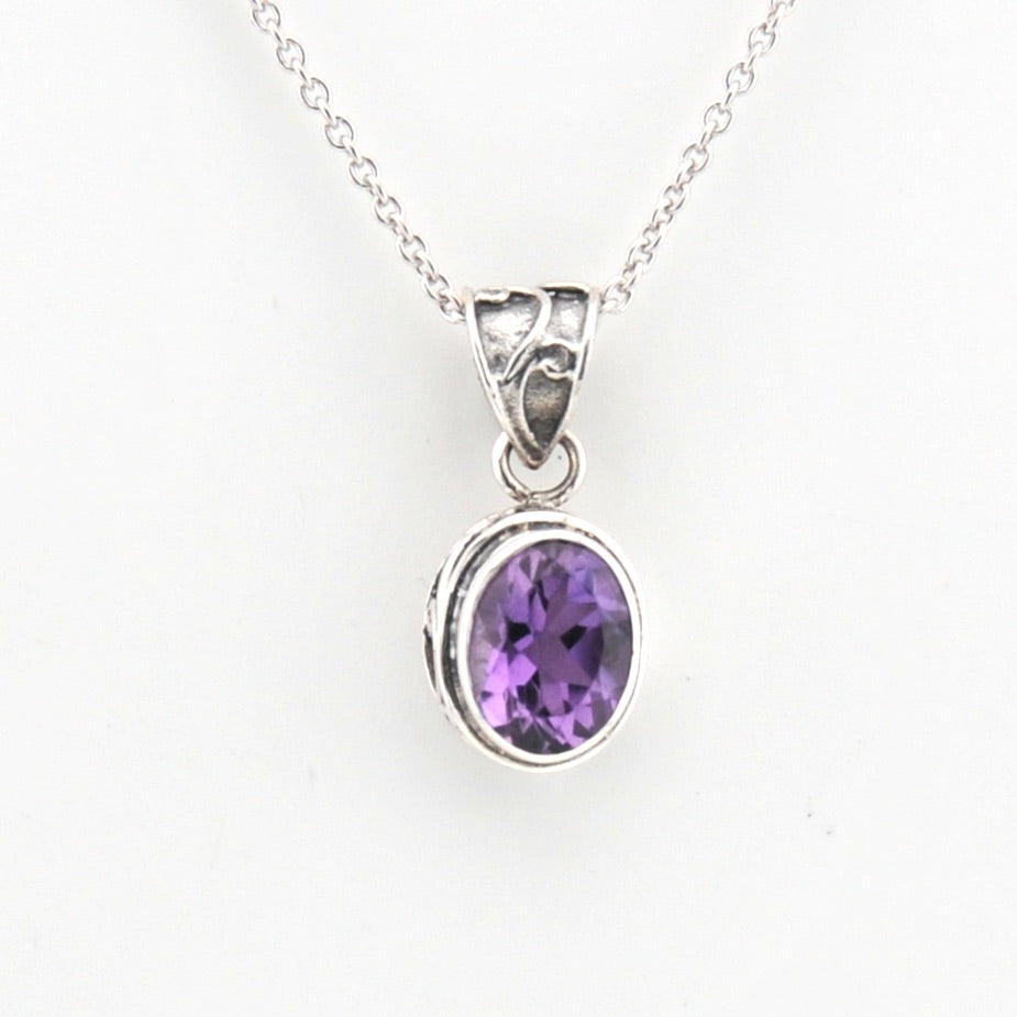 Silver pendant with a purple gemstone on a white background