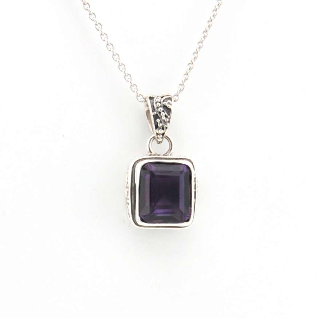 Silver necklace with a purple gemstone pendant on a white background