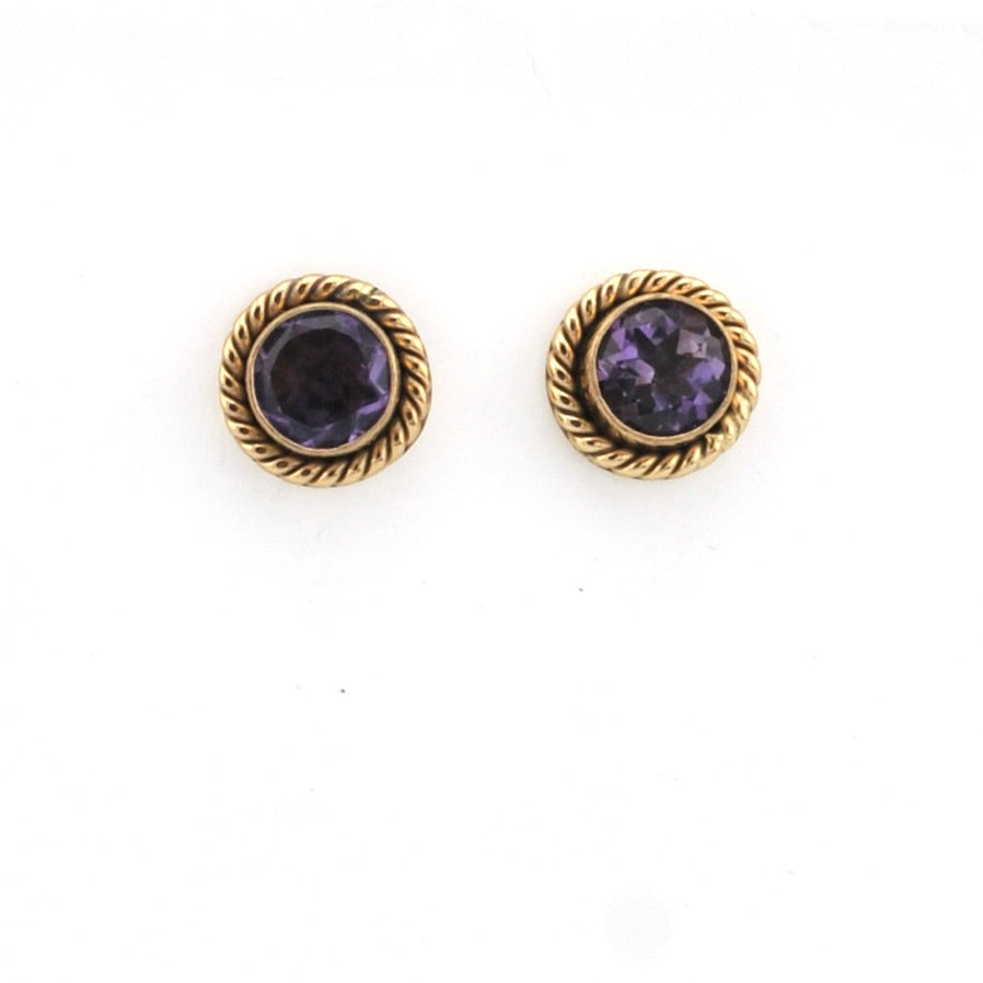 Pair of gold earrings with purple gemstones on a white background