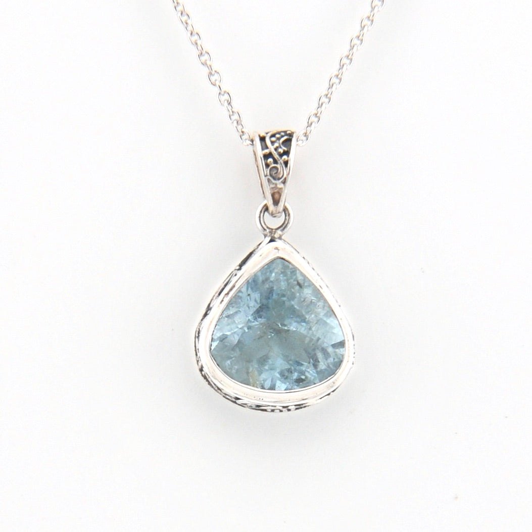 Teardrop-shaped blue gemstone pendant on a silver chain against a white background