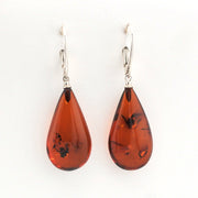 Teardrop-shaped amber earrings with silver hooks on a white background