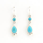 Turquoise teardrop earrings with silver hooks on a white background