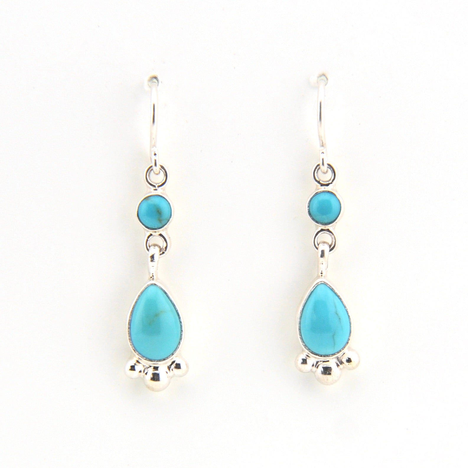 Turquoise teardrop earrings with silver hooks on a white background