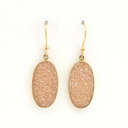 Pair of gold earrings with beige stone drops on a white background