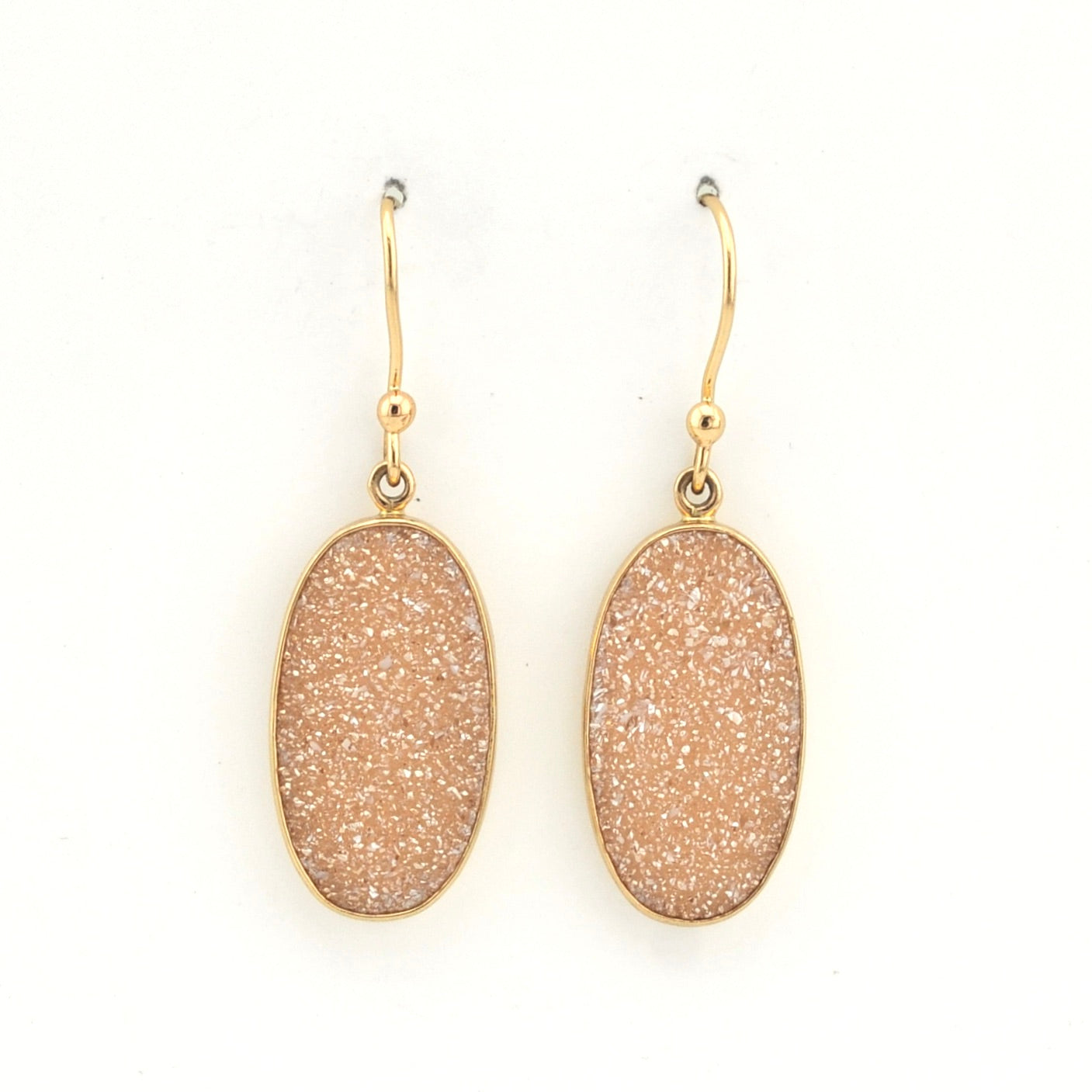 Pair of gold earrings with beige stone drops on a white background