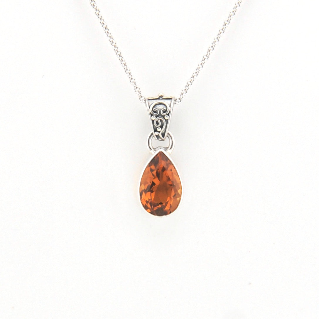 Teardrop-shaped citrine pendant on a silver chain against a white background