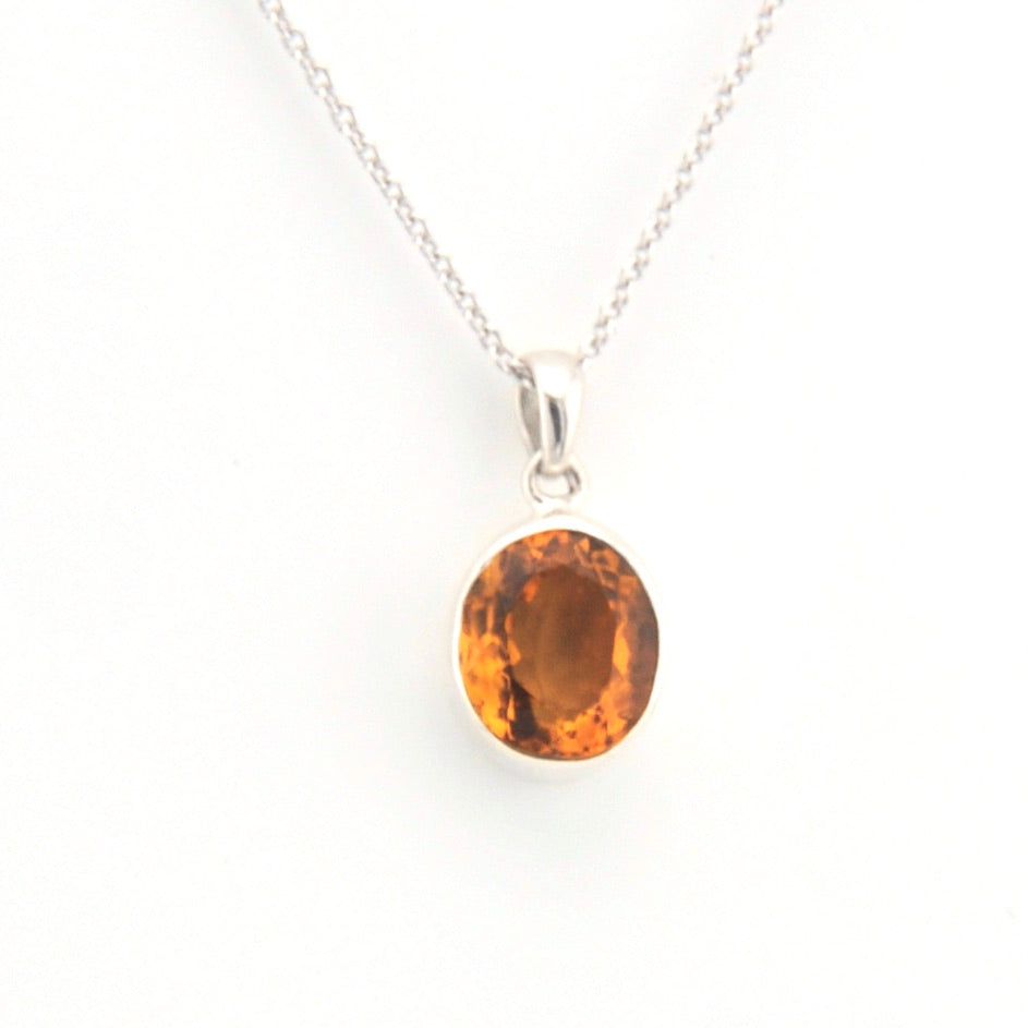 Silver necklace with a pendant featuring an citrine gemstone on a white background