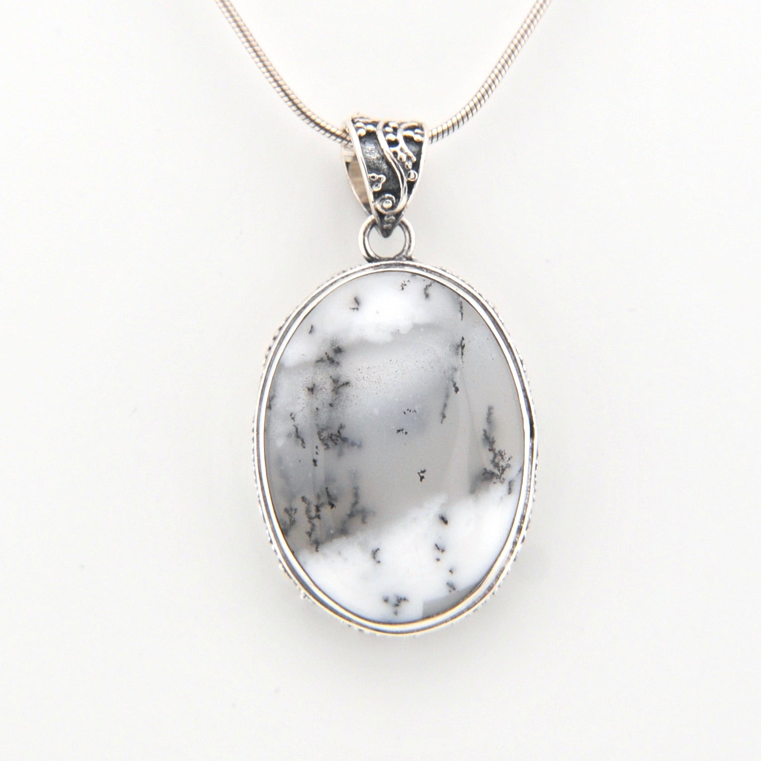 Pendant with white marbled stone and silver frame on a white background