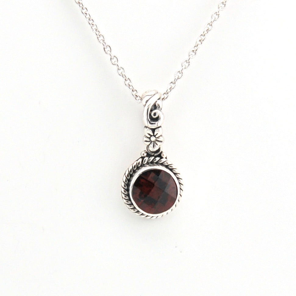 Silver necklace with a garnet pendant on a white background