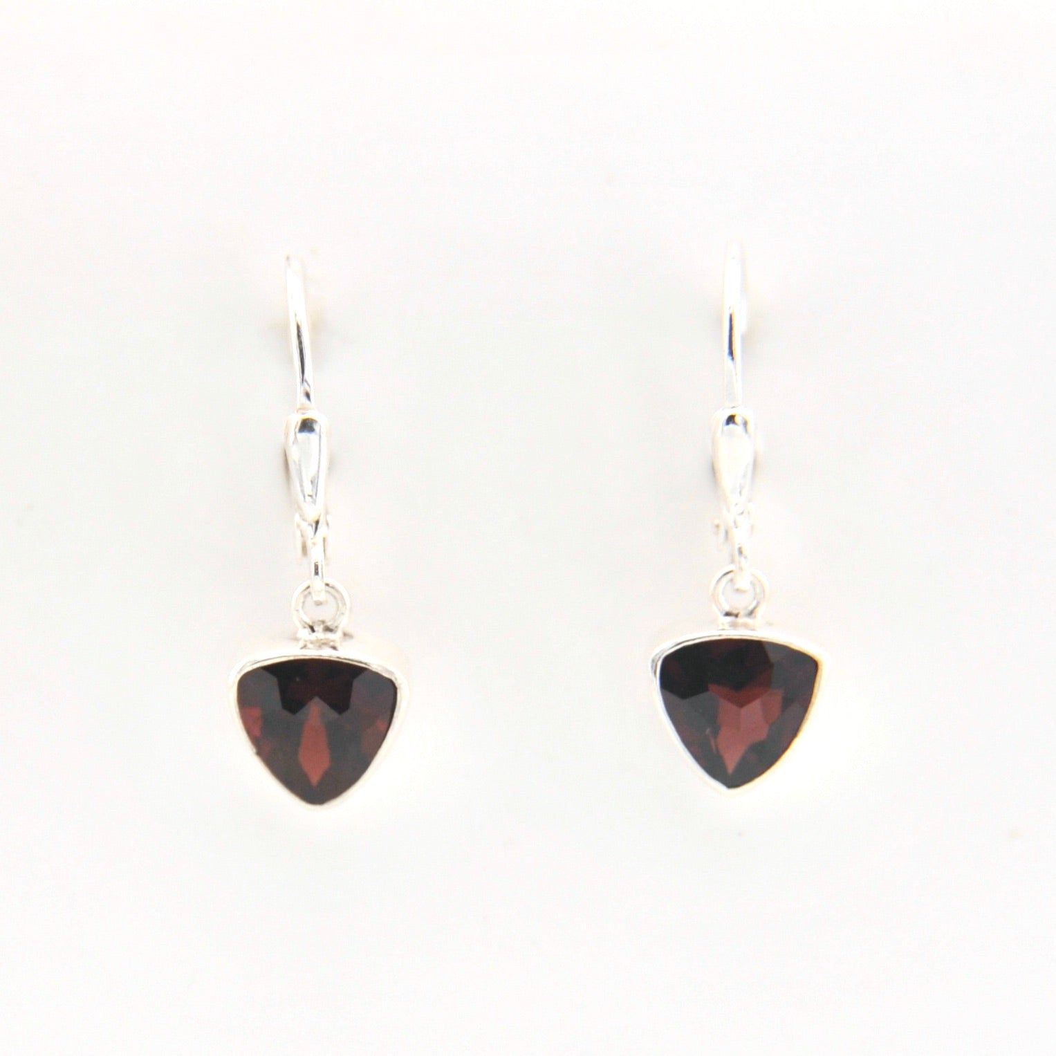 Pair of silver earrings with red gemstones on a white background
