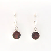 Pair of earrings with round dark red gemstones on white background