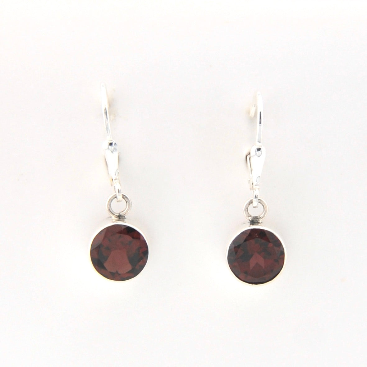 Pair of earrings with round dark red gemstones on white background