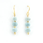 Pair of earrings with light blue beads and gold hooks on a white background