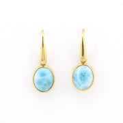 A pair of gold drop earrings with oval light blue marbled gemstone bezels, shown on a plain white background.