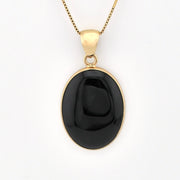 Black pendant on a gold chain against a white background