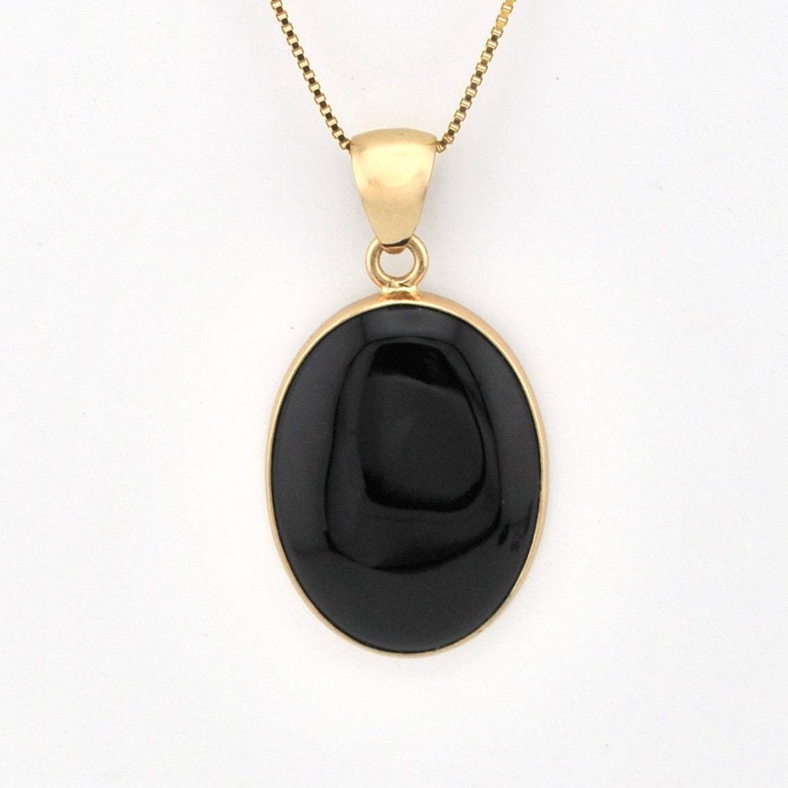Black pendant on a gold chain against a white background