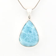 Teardrop-shaped larimar pendant on a silver chain against a white background
