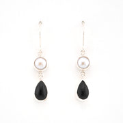 Pair of earrings with black teardrop-shaped stones and pearl-like tops on a white background