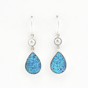 Teardrop-shaped blue glitter earrings with pearl accents on a white background