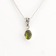 Green gemstone pendant on a silver chain against a white background