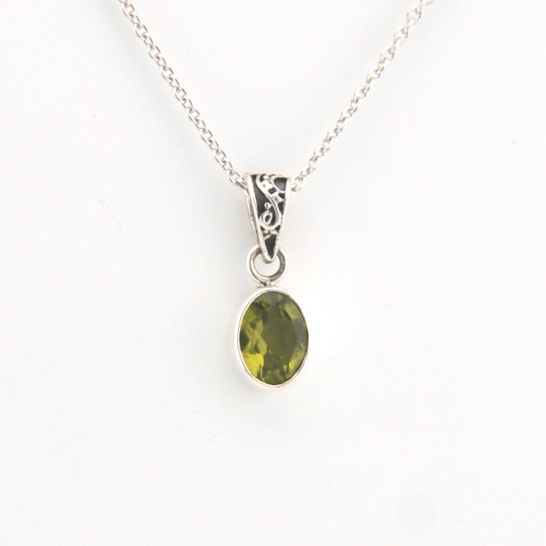 Green gemstone pendant on a silver chain against a white background