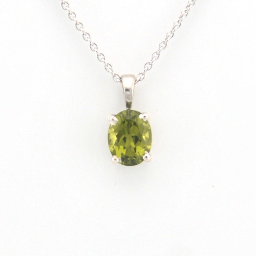 Green gemstone pendant on a silver chain against a white background