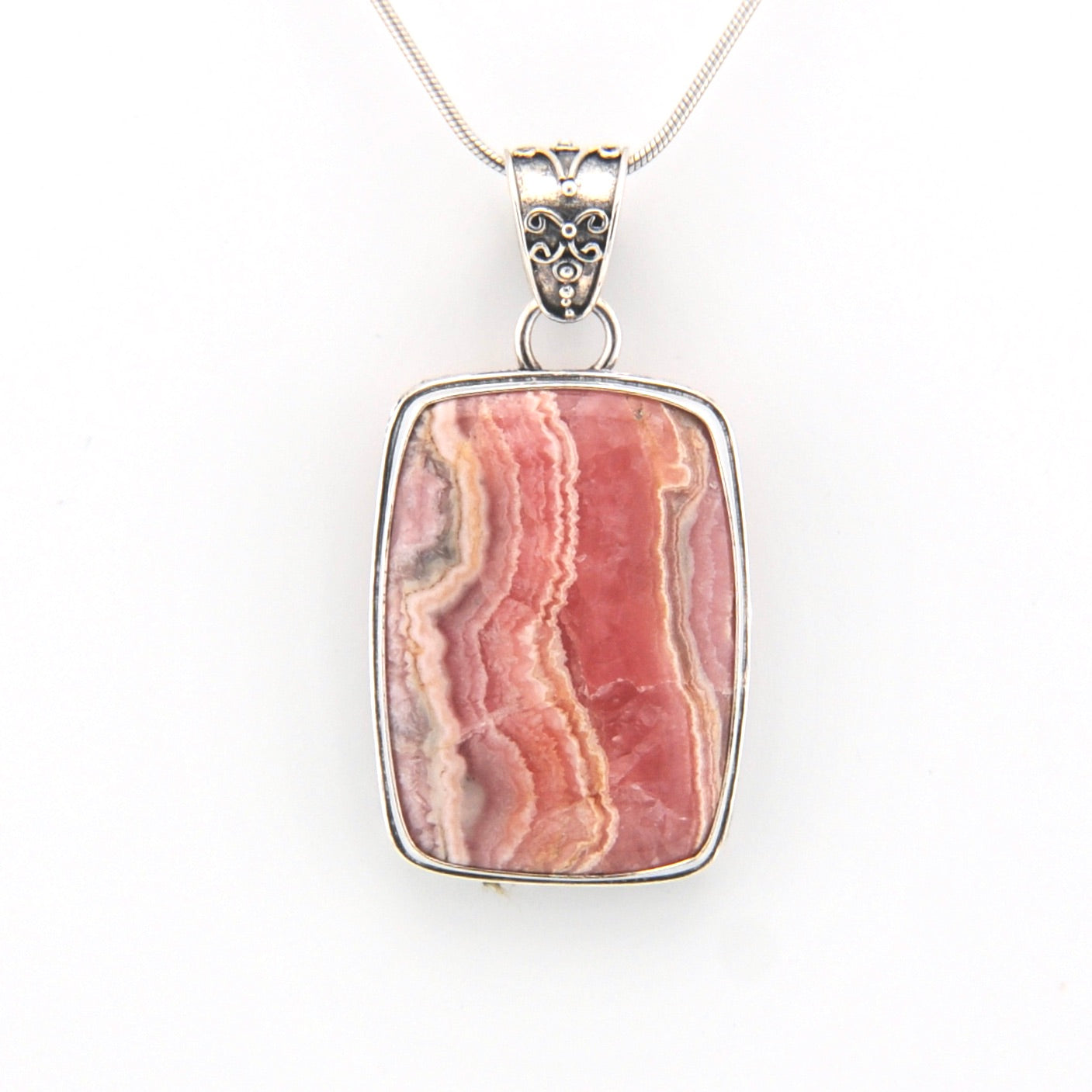 Pendant with pink stone and silver chain on a white background