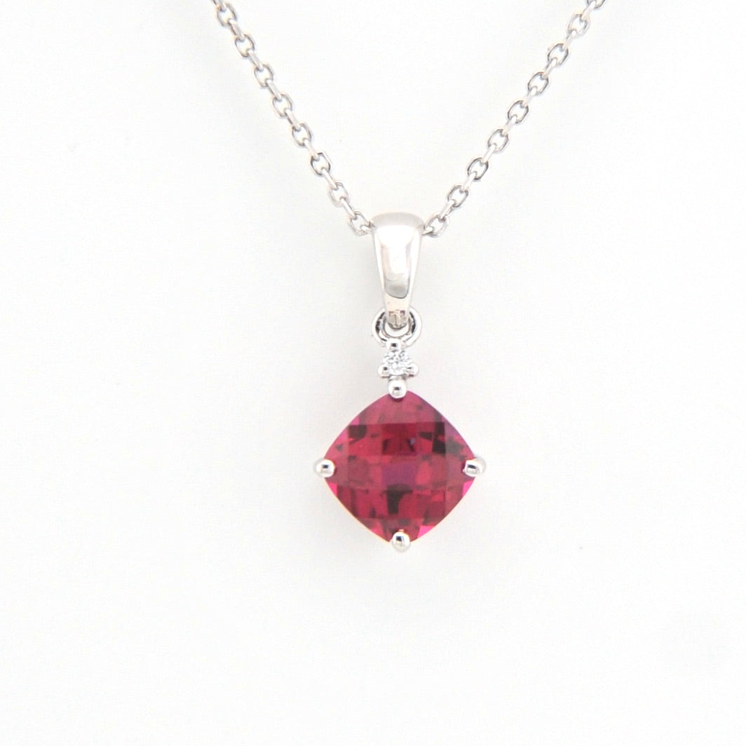 Silver necklace with a red gemstone pendant on a white background
