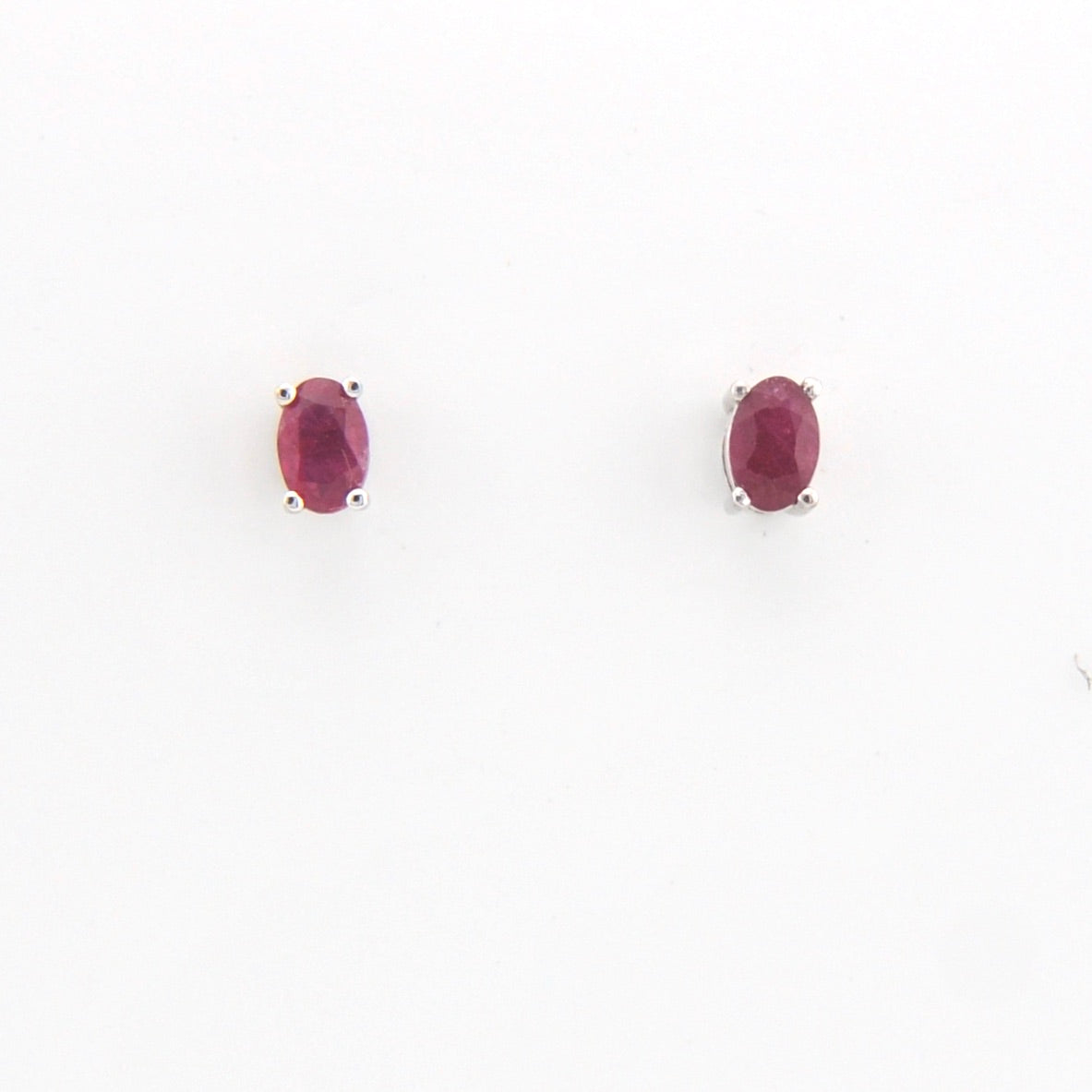 Pair of oval-shaped ruby gemstones on a white background