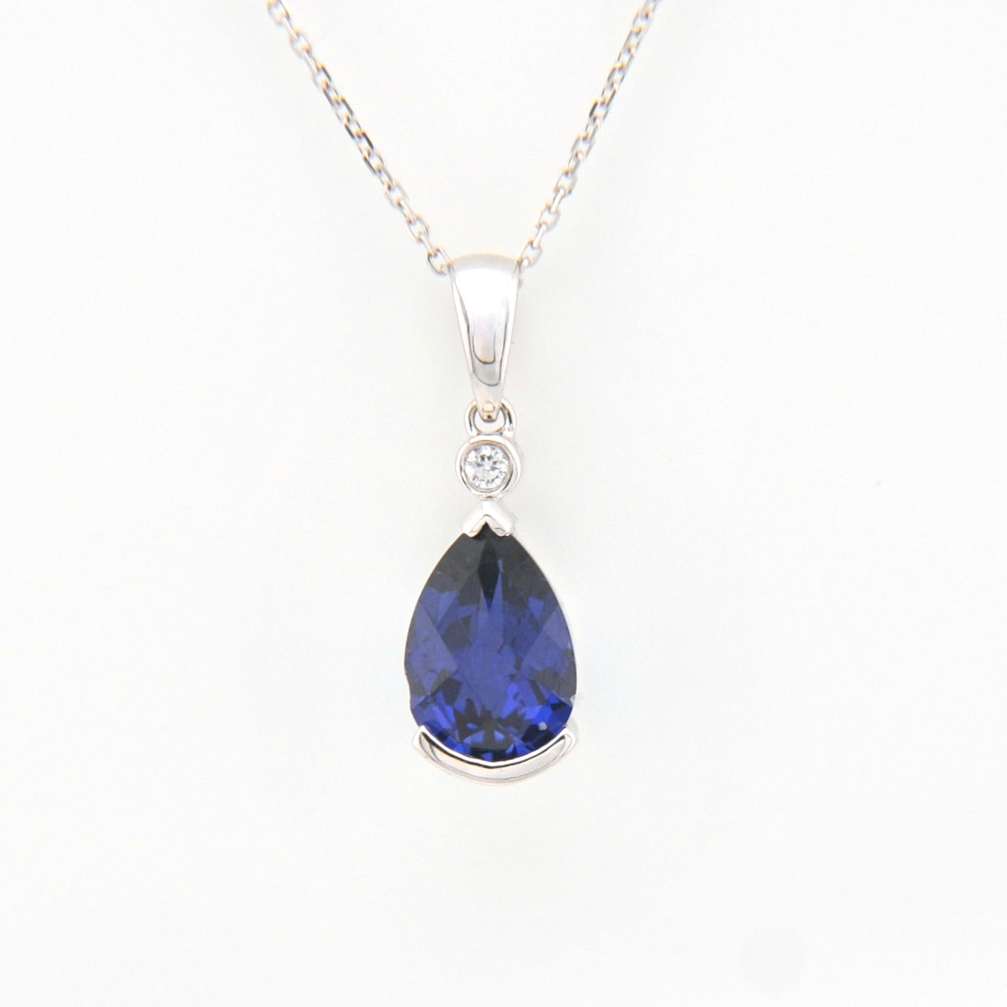Teardrop-shaped blue gemstone pendant on a white background
