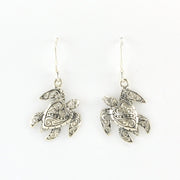 A pair of silver-toned sea turtle drop earrings with intricate filigree detailing, shown against a plain white background.
