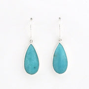 A pair of silver drop earrings featuring teardrop-shaped turquoise blue gemstones, displayed against a clean white background.