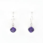 Purple gemstone earrings on silver hooks against a white background