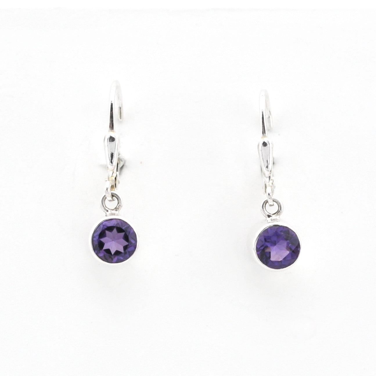 Pair of silver earrings with purple gemstones on a white background