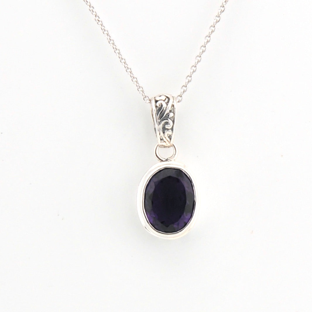 Silver pendant with a purple gemstone on a white background