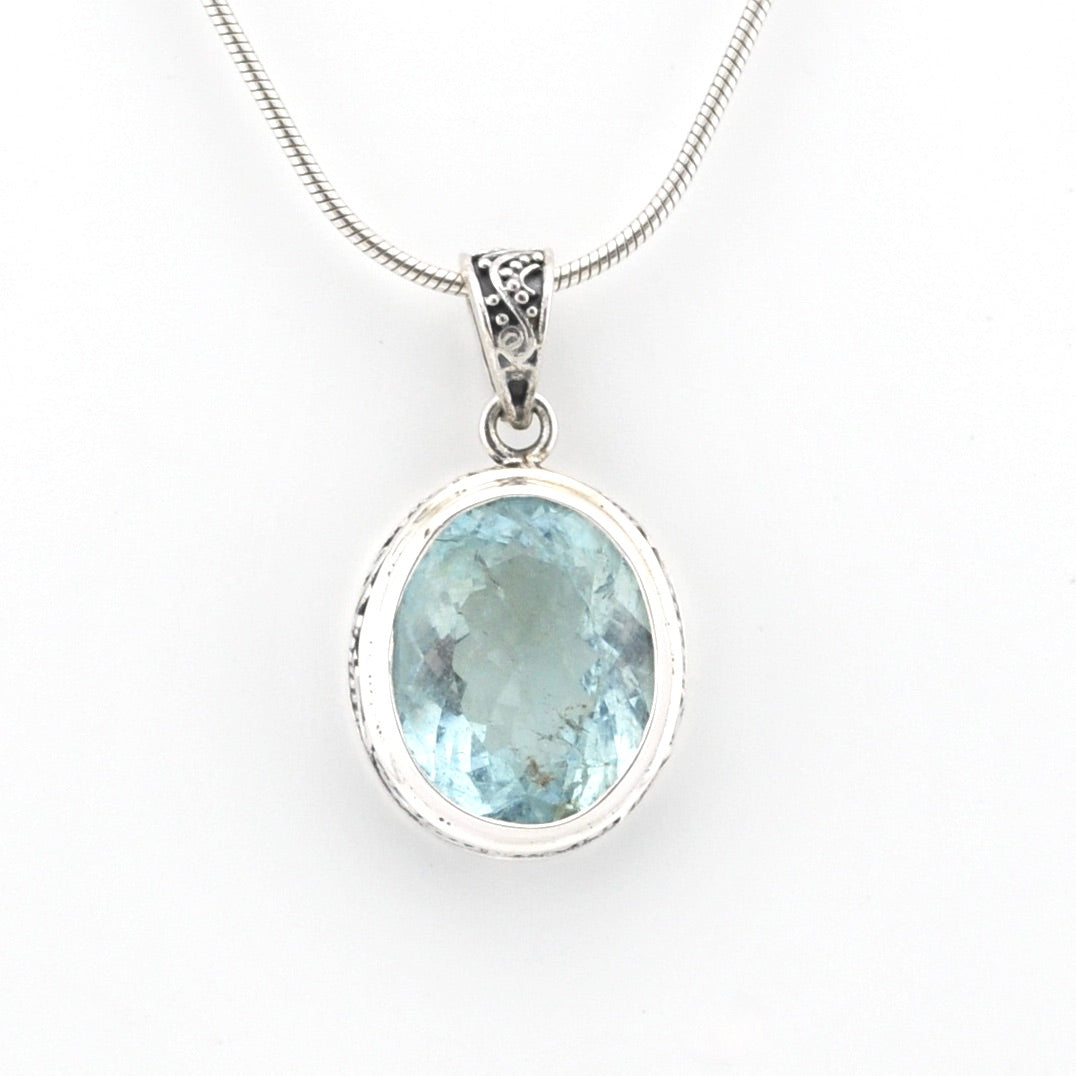 Silver pendant with a blue gemstone on a white background