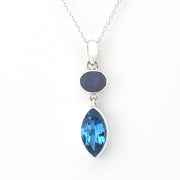 A silver pendant necklace featuring a marquise-cut light blue gemstone and an oval dark blue gemstone set in a silver bezel, suspended from a delicate silver chain against a white background.