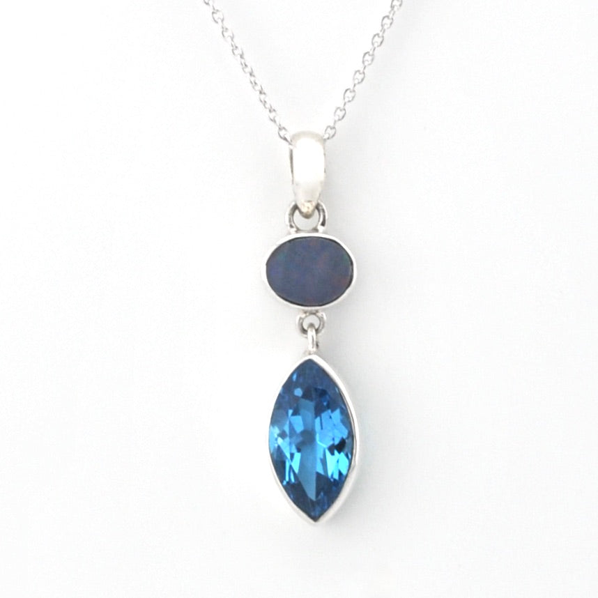 A silver pendant necklace featuring a marquise-cut light blue gemstone and an oval dark blue gemstone set in a silver bezel, suspended from a delicate silver chain against a white background.