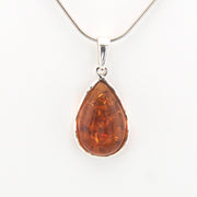 Teardrop-shaped amber pendant on a silver chain against a white background