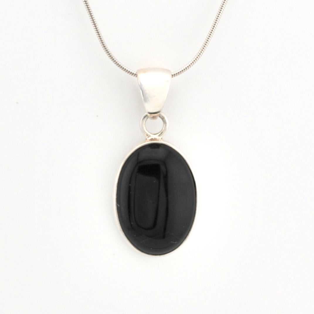 Black oval pendant on a silver chain against a white background