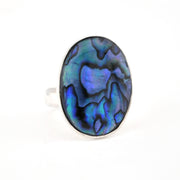 Ring with a colorful abalone shell stone on a white background