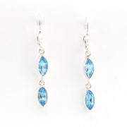 Pair of silver earrings with blue gemstones on a white background