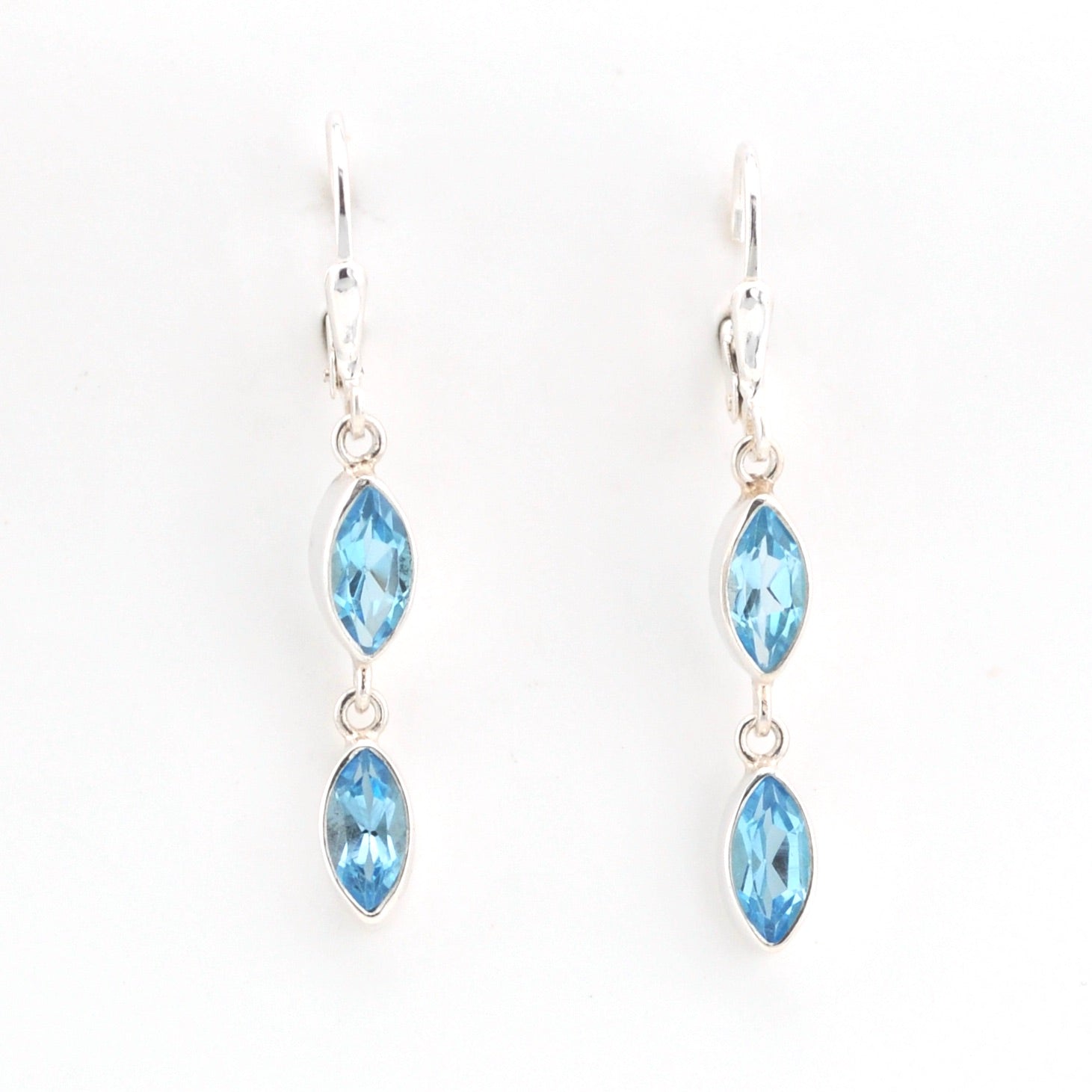 Pair of silver earrings with blue gemstones on a white background