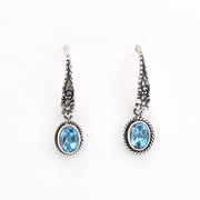Pair of silver earrings with blue gemstones on a white background