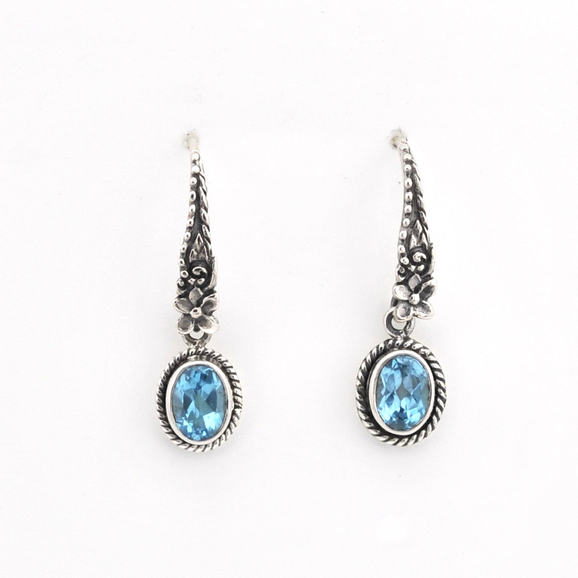 Pair of silver earrings with blue gemstones on a white background