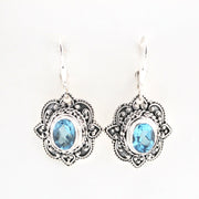 Pair of silver earrings with blue gemstones on a white background